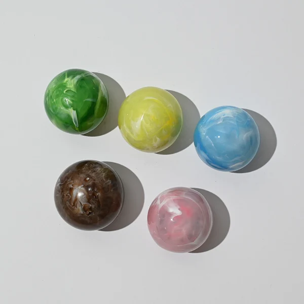 HUA0042 perfume bottle, clear flattened oval flask glass bottle featuring a prominent spherical ball-shaped resin cap with an eye-catching marbled texture and organic fluid swirls, modern playful fragrance packaging design available in 30ml, 50ml, and 100ml