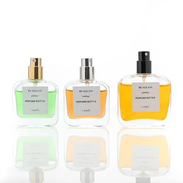 HUA0052 perfume bottle, heavy-base clear flattened oval flask glass bottle, featuring a square paper label and a tall cylindrical plastic cap with a smooth high-gloss shiny finish, elegant modern fragrance packaging design available in 30ml, 50ml, and 100ml
