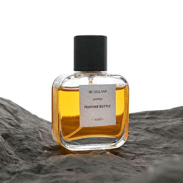 HUA0052 perfume bottle, heavy-base clear flattened oval flask glass bottle, featuring a square paper label and a tall cylindrical plastic cap with a smooth high-gloss shiny finish, elegant modern fragrance packaging design available in 30ml, 50ml, and 100ml