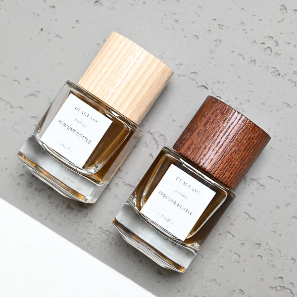 HUA0008 perfume bottle, luxury heavy-base cylindrical glass bottle with high-transparency clear finish, featuring a square paper label and a prominent tall flush-fit cylindrical natural textured wooden cap showcasing deep vertical wood grains, minimalist elegant fragrance packaging design available in 30ml, 50ml, and 100ml