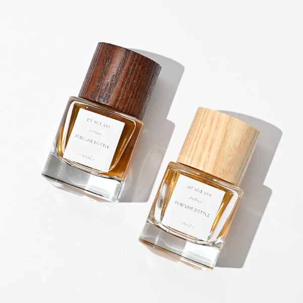 HUA0008 perfume bottle, luxury heavy-base cylindrical glass bottle with high-transparency clear finish, featuring a square paper label and a prominent tall flush-fit cylindrical natural textured wooden cap showcasing deep vertical wood grains, minimalist elegant fragrance packaging design available in 30ml, 50ml, and 100ml