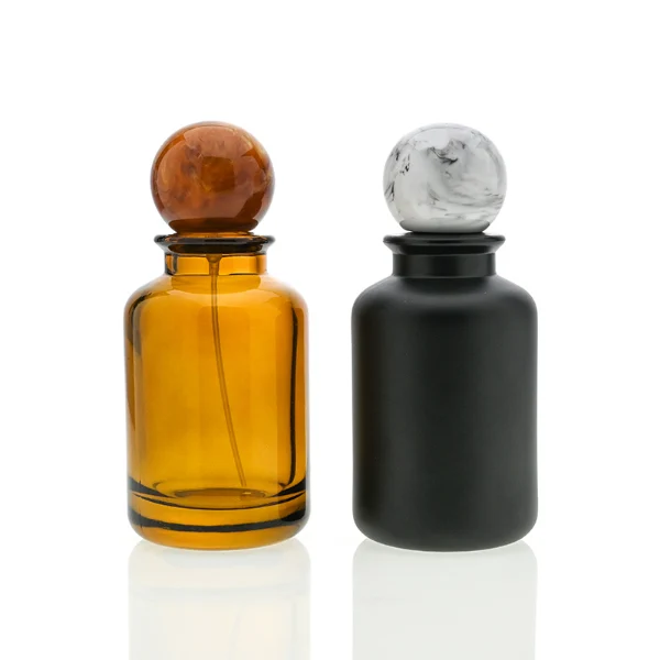 HUA0044 perfume bottle, cylindrical round glass bottle in high-transparency amber or solid high-gloss opaque black finish, featuring a prominent spherical ball-shaped resin cap with an eye-catching marbled texture and organic fluid swirls, elegant modern fragrance packaging design available in 30ml, 50ml, and 100ml
