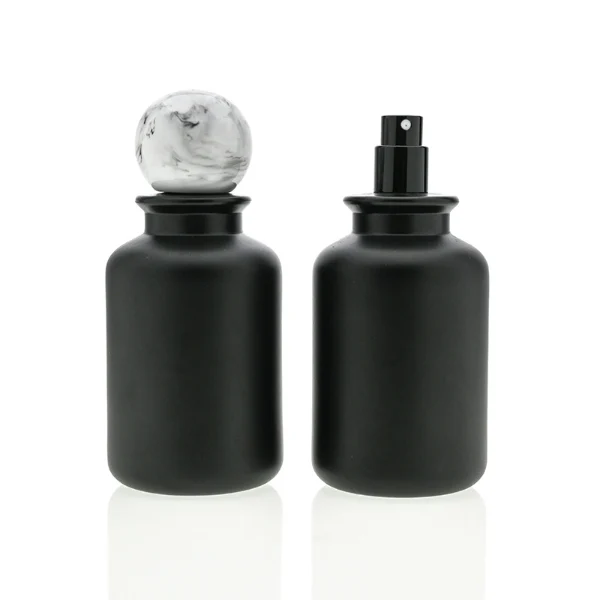 HUA0044 perfume bottle, cylindrical round glass bottle in high-transparency amber or solid high-gloss opaque black finish, featuring a prominent spherical ball-shaped resin cap with an eye-catching marbled texture and organic fluid swirls, elegant modern fragrance packaging design available in 30ml, 50ml, and 100ml