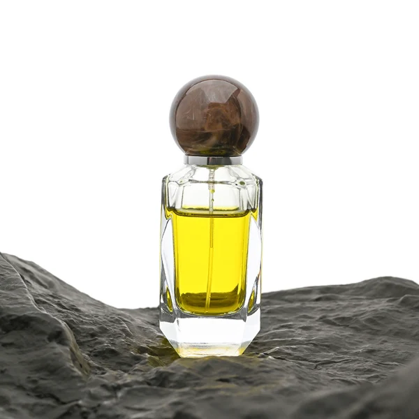 HUA0034 perfume bottle, heavy-base cylindrical glass bottle with a faceted shoulder and clear finish, featuring a square paper label, a polished gold or silver neck, and a tall cylindrical resin cap with a colorful marbled finish, elegant modern fragrance packaging design available in 50ml