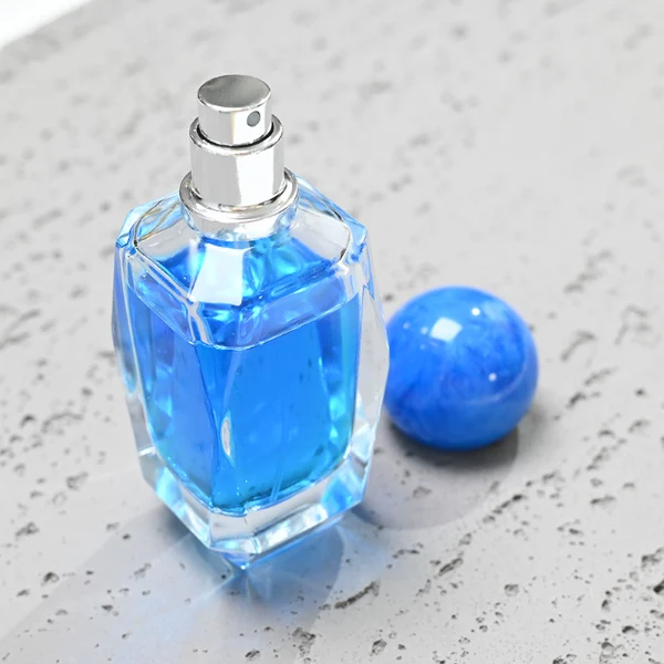 HUA0034 perfume bottle, heavy-base cylindrical glass bottle with a faceted shoulder and clear finish, featuring a square paper label, a polished gold or silver neck, and a tall cylindrical resin cap with a colorful marbled finish, elegant modern fragrance packaging design available in 50ml