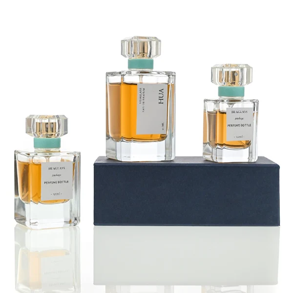 Vintage-inspired clear square plastic caps with a light mint green neck accent ring. Elegant square perfume bottles crafted from heavy-base clear glass filled with golden-amber liquid.