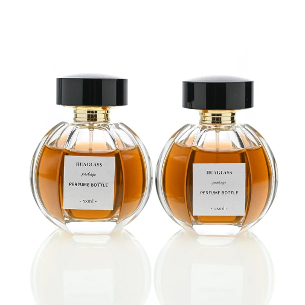 HUA0012 perfume bottle, heavy-base ribbed spherical round glass bottle with clear finish, featuring a square paper label, a matching neck, and a wide cylindrical plastic cap with a smooth high-gloss shiny black finish, elegant modern fragrance packaging design available in 100ml