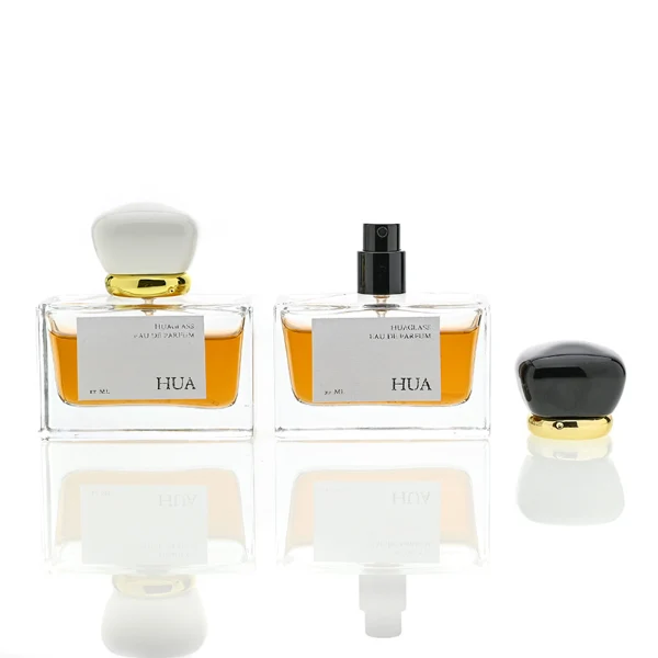 HUA0015 perfume bottle, heavy-base wide rectangular glass bottle with clear finish, featuring a square paper label, a polished gold neck, and a cushion-shaped plastic cap with a smooth high-gloss shiny finish, elegant modern fragrance packaging design available in 30ml, 50ml, and 100ml