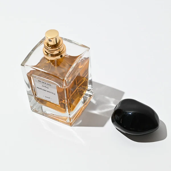 HUA0066 perfume bottles, rectangular clear glass with irregular black plastic caps, amber liquid, modern elegant design, 50ml 100ml.