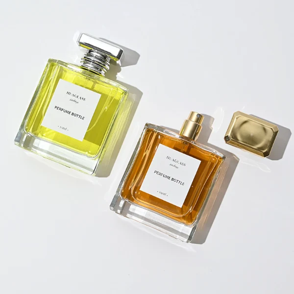 HUA0068 perfume bottles, rectangular clear glass with gold and silver rectangular plastic caps, amber and yellow liquids, modern elegant design, 50ml 100ml.