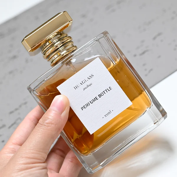 HUA0068 perfume bottles, rectangular clear glass with gold and silver rectangular plastic caps, amber and yellow liquids, modern elegant design, 50ml 100ml.