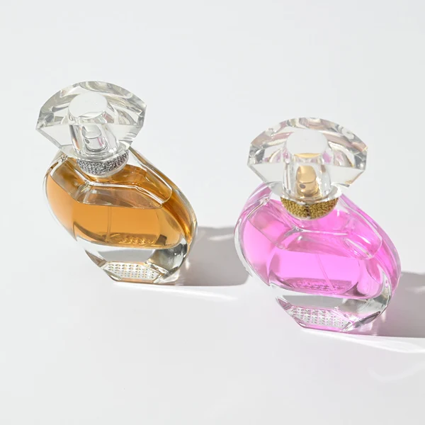 HUA0069 perfume bottles, oval clear glass with faceted plastic caps in silver/gold tones, amber and pink liquids, modern elegant design, 30ml 50ml 100ml.