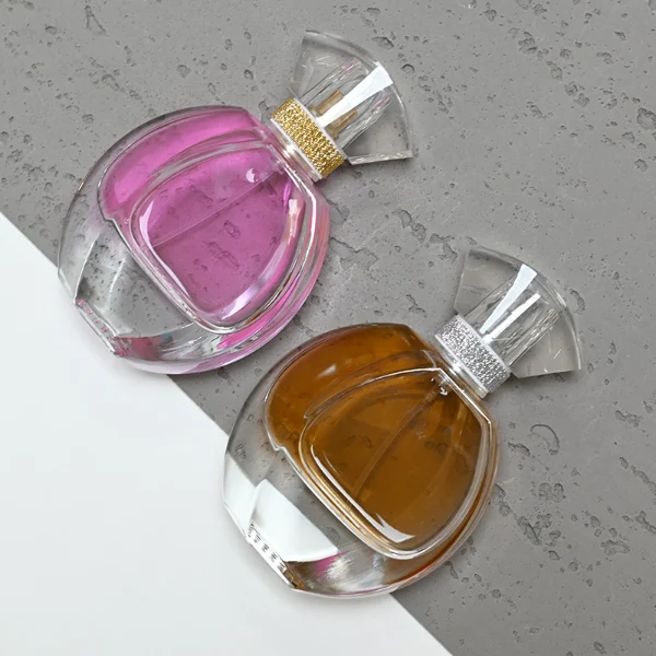 HUA0069 perfume bottles, oval clear glass with faceted plastic caps in silver/gold tones, amber and pink liquids, modern elegant design, 30ml 50ml 100ml.
