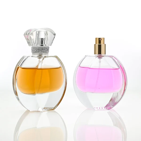 HUA0069 perfume bottles, oval clear glass with faceted plastic caps in silver/gold tones, amber and pink liquids, modern elegant design, 30ml 50ml 100ml.