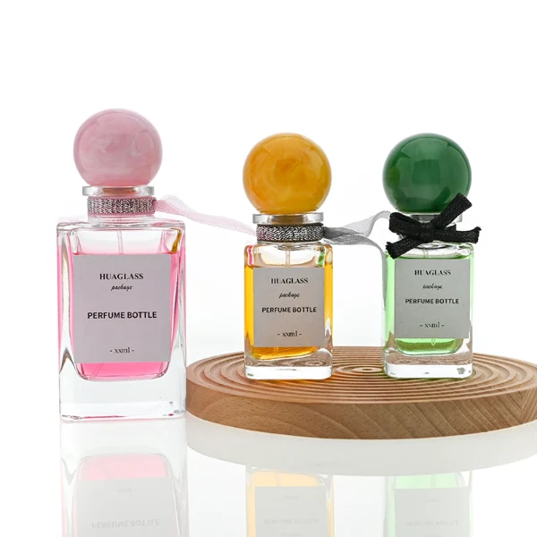HUA0070 perfume bottles, rectangular clear glass with round colorful resin caps and metallic collars, pink and purple liquids, modern elegant design, 30ml 50ml 100ml.