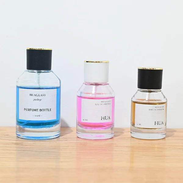 HUA0072 perfume bottle, clear cylindrical glass with liquid, white or black plastic cap with gold ring stripe on top, modern elegant design, available in 30 ml, 50 ml, and 100 ml