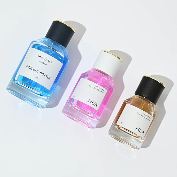 HUA0072 perfume bottle, clear cylindrical glass with liquid, white or black plastic cap with gold ring stripe on top, modern elegant design, available in 30 ml, 50 ml, and 100 ml