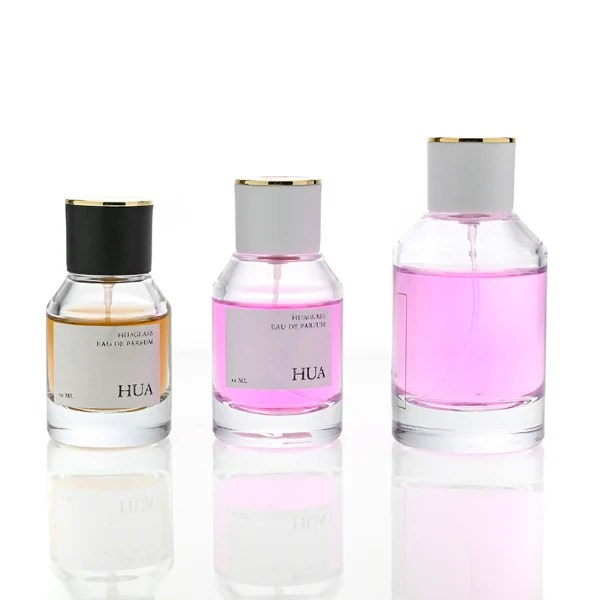 HUA0072 perfume bottle, clear cylindrical glass with liquid, white or black plastic cap with gold ring stripe on top, modern elegant design, available in 30 ml, 50 ml, and 100 ml