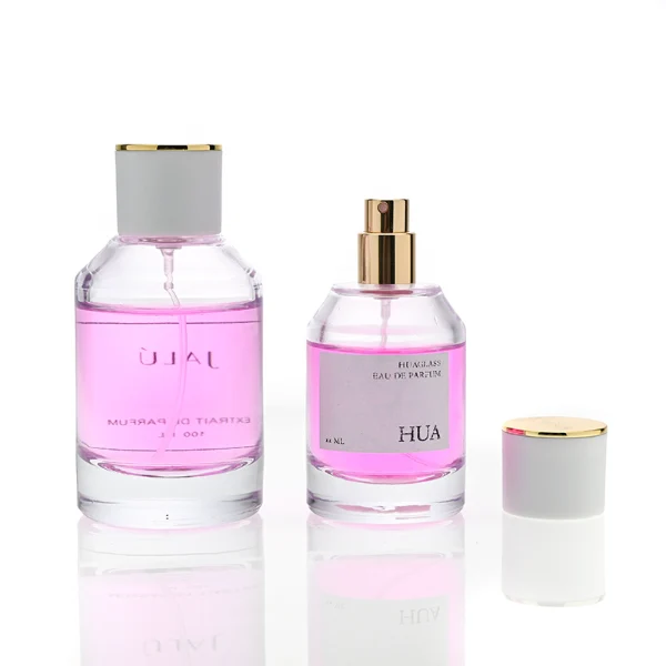 HUA0072 perfume bottle, clear cylindrical glass with liquid, white or black plastic cap with gold ring stripe on top, modern elegant design, available in 30 ml, 50 ml, and 100 ml