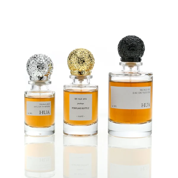 HUA0076 perfume bottle, cylindrical clear glass with liquid, ornate textured spherical cap in silver gold or black finish, modern elegant design, available in 35 ml, 50 ml, and 100 ml
