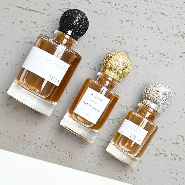 HUA0076 perfume bottle, cylindrical clear glass with liquid, ornate textured spherical cap in silver gold or black finish, modern elegant design, available in 35 ml, 50 ml, and 100 ml