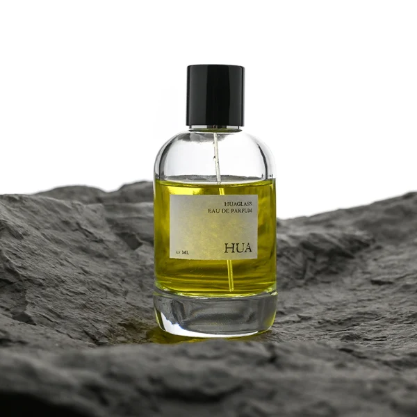 HUA0077 perfume bottle, rounded clear glass with liquid, glossy black aluminum magnetic cap, modern elegant design, available in 50 ml and 100 ml