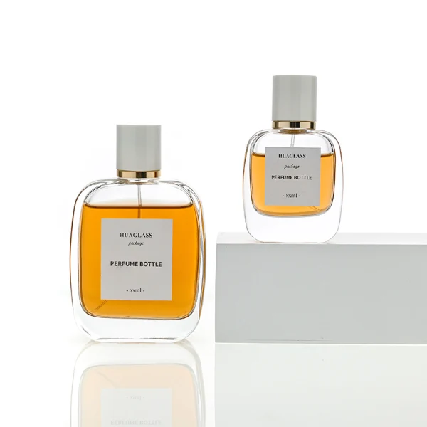 HUA0078 perfume bottle, rounded rectangular clear glass with liquid, glossy white cylindrical cap with gold ring below the cap, modern elegant design, available in 30 ml, 50 ml, and 100 ml
