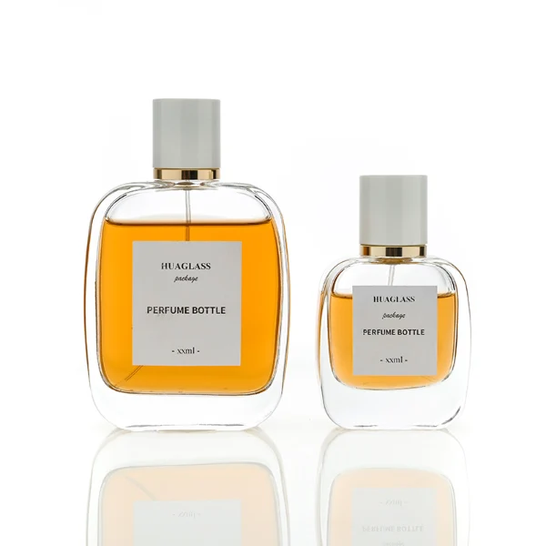 HUA0078 perfume bottle, rounded rectangular clear glass with liquid, glossy white cylindrical cap with gold ring below the cap, modern elegant design, available in 30 ml, 50 ml, and 100 ml