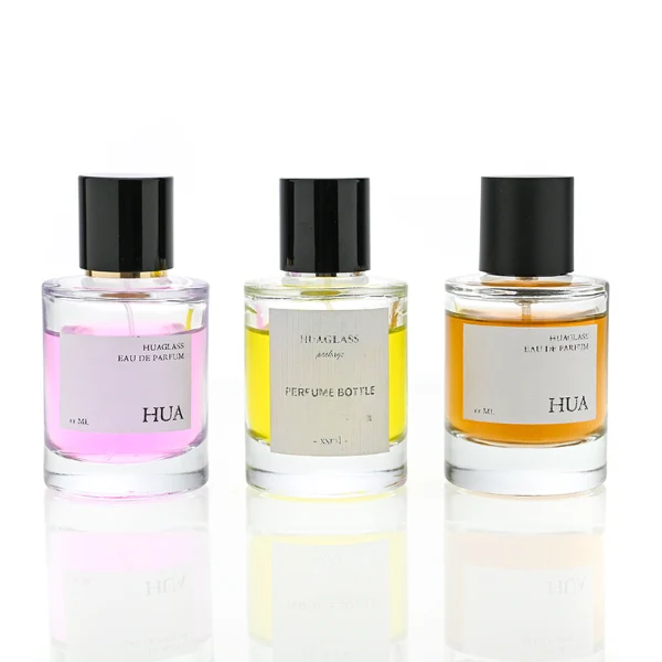 HUA0079 perfume bottle, cylindrical clear glass with liquid, glossy black aluminum magnetic cap, modern minimalist design, available in 30 ml, 50 ml, and 100 ml