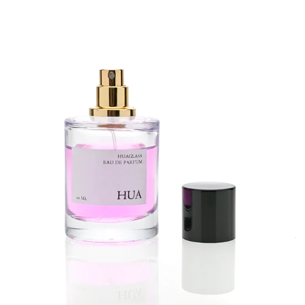 HUA0079 perfume bottle, cylindrical clear glass with liquid, glossy black aluminum magnetic cap, modern minimalist design, available in 30 ml, 50 ml, and 100 ml