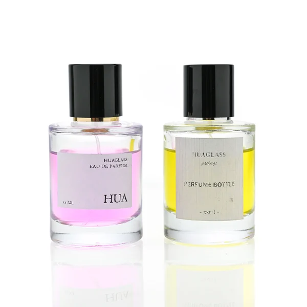 HUA0079 perfume bottle, cylindrical clear glass with liquid, glossy black aluminum magnetic cap, modern minimalist design, available in 30 ml, 50 ml, and 100 ml