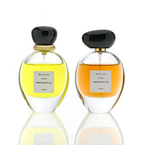 HUA0080 perfume bottle, oval internally sprayed glass with liquid, glossy black rounded plastic cap with irregular gold edge texture, modern elegant design, available in 30 ml, 50 ml, 75 ml, and 100 ml