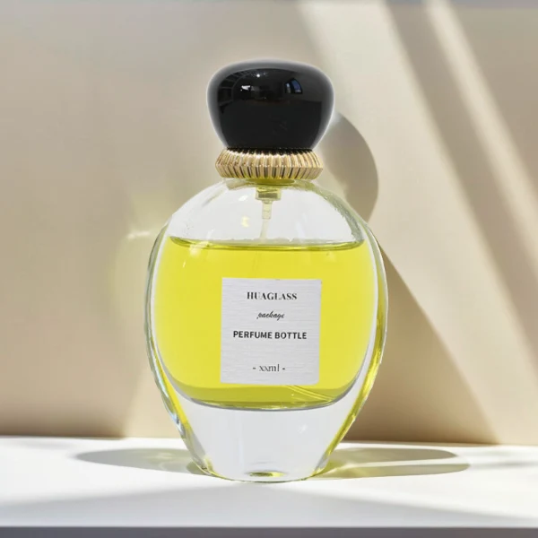 HUA0080 perfume bottle, oval internally sprayed glass with liquid, glossy black rounded plastic cap with irregular gold edge texture, modern elegant design, available in 30 ml, 50 ml, 75 ml, and 100 ml