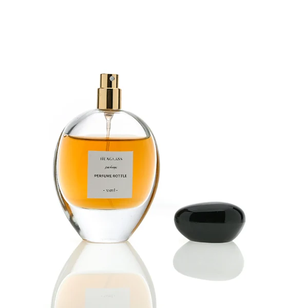 HUA0080 perfume bottle, oval internally sprayed glass with liquid, glossy black rounded plastic cap with irregular gold edge texture, modern elegant design, available in 30 ml, 50 ml, 75 ml, and 100 ml