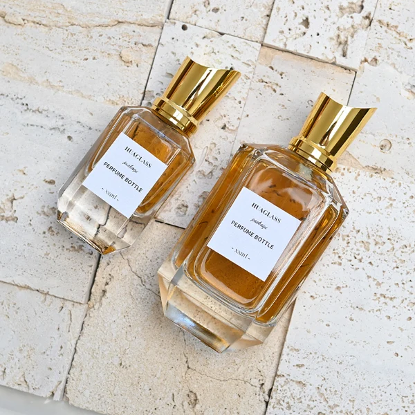 HUA0082 perfume bottle, cylindrical clear glass body, spherical glossy plastic cap with engraved patterns and glass neck, modern luxurious design, available in 30 ml, 50 ml, and 100 ml.