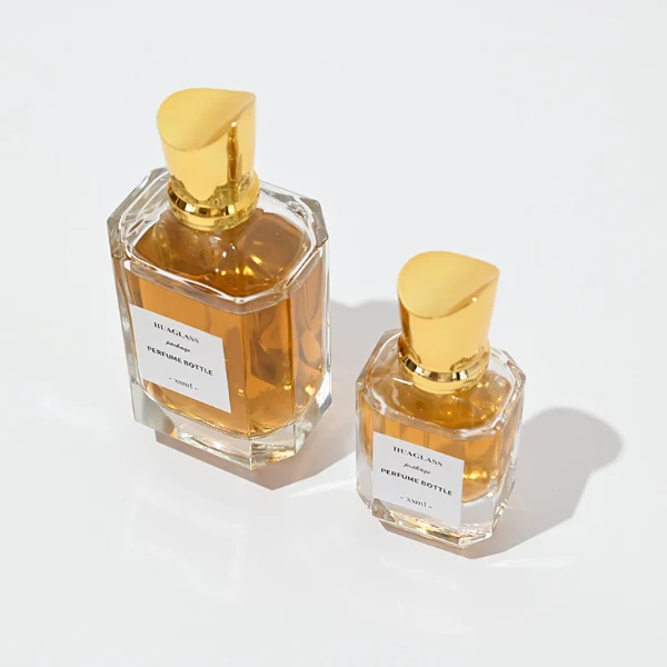 HUA0082 perfume bottle, cylindrical clear glass body, spherical glossy plastic cap with engraved patterns and glass neck, modern luxurious design, available in 30 ml, 50 ml, and 100 ml.