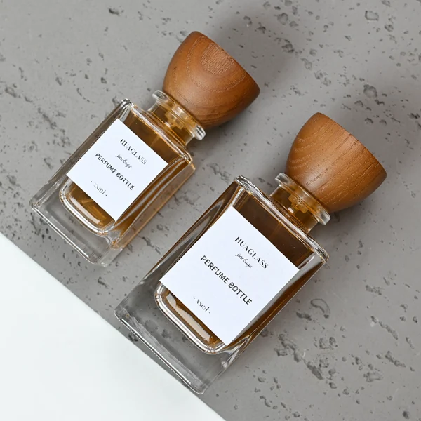 HUA0083 perfume bottle, square clear glass, wooden stopper-style cap, modern elegant design, available in 30 ml, 50 ml, and 100 ml