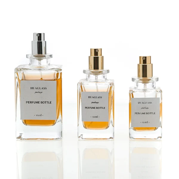 HUA0085 perfume bottle, rectangular clear glass body with liquid, irregular spherical plastic cap with glass neck, modern elegant design, available in 30 ml, 50 ml, and 100 ml.