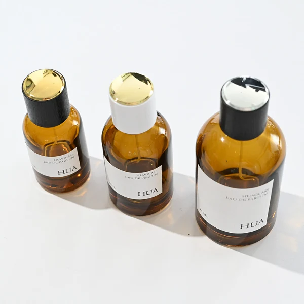 HUA0089 perfume bottle, cylindrical clear glass body with liquid, glossy plastic cylindrical cap with metallic neck, modern minimalist design, available in 30 ml, 50 ml, and 100 ml.