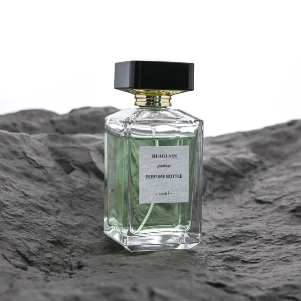 HUA0092 perfume bottle, rectangular column clear glass body with green-tinted liquid, black flat rectangular plastic cap, modern minimalist design, available in 30 ml, 50 ml, and 100 ml.