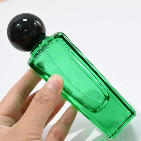 HUA0095 perfume bottle, tall rectangular colored glass body with embossed side details, glossy spherical plastic cap, modern artistic design, available in 50 ml.