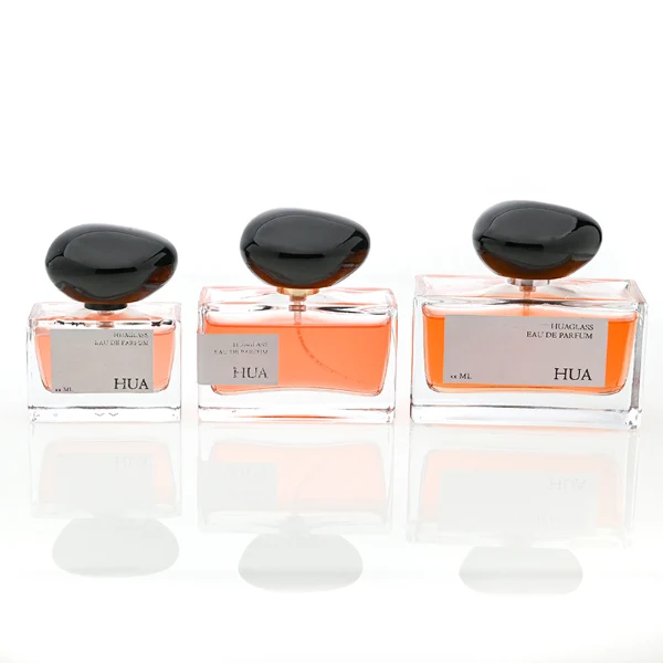 HUA0096 perfume bottle, rectangular glass body, glossy black pebble-shaped plastic cap with yellow accents, modern minimalist design, available in 30 ml, 50 ml, and 100 ml.
