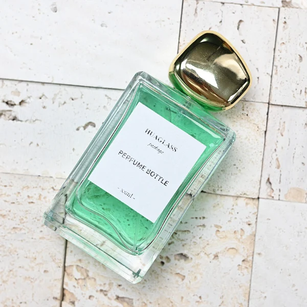 HUA0097 perfume bottle, rectangular glass body with liquid, glossy irregular rounded plastic cap, modern elegant design, available in 100 ml.