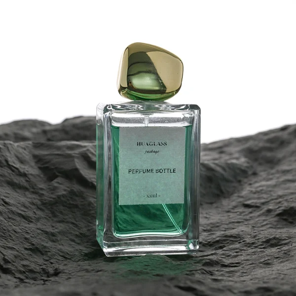 HUA0097 perfume bottle, rectangular glass body with liquid, glossy irregular rounded plastic cap, modern elegant design, available in 100 ml.