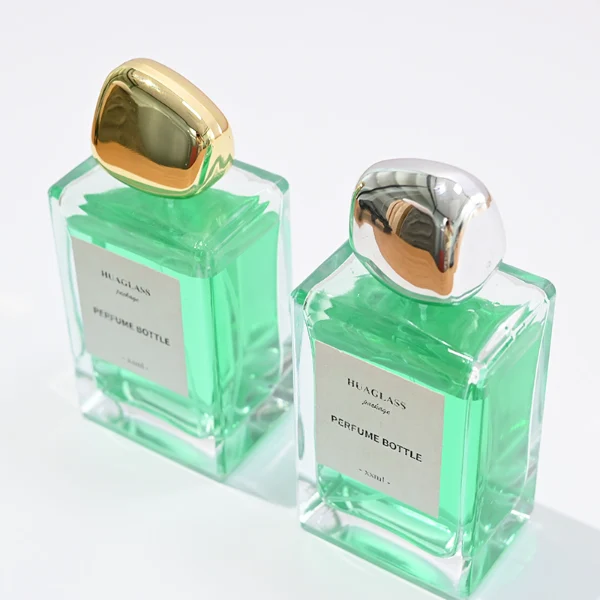 HUA0097 perfume bottle, rectangular glass body with liquid, glossy irregular rounded plastic cap, modern elegant design, available in 100 ml.