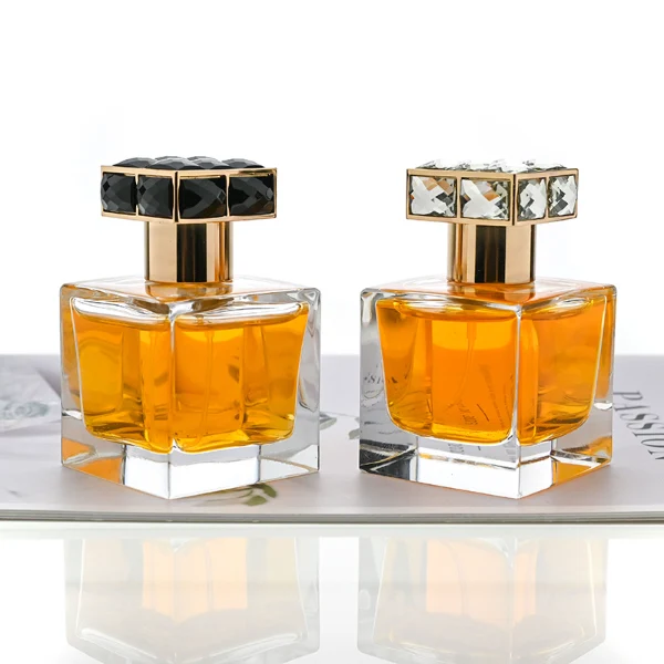 HUA0100 perfume bottle, square glass body with liquid, rectangular geometric zinc alloy cap with colorful crystal detailing on the top, modern luxurious design, available in 30 ml, 50 ml, and 100 ml.