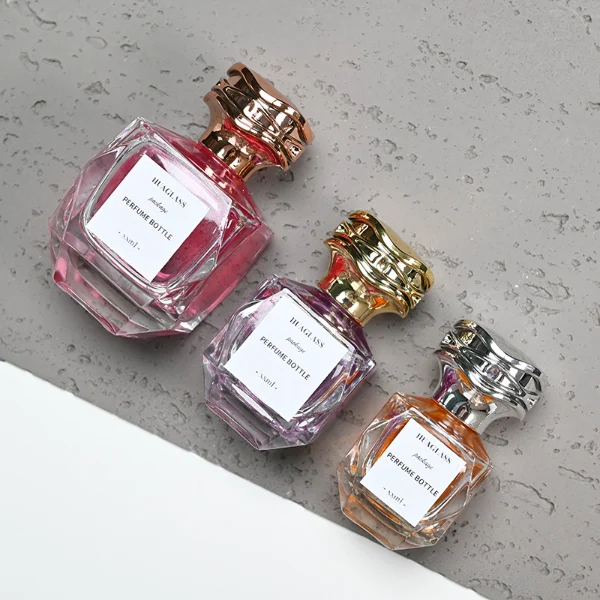 HUA0101 perfume bottle, faceted glass body with liquid, layered wave-shaped plastic cap, neck with bright metallic finish in gold, silver, or copper and FEA15-crimp specification, modern elegant design, available in 30 ml, 50 ml, and 100 ml.