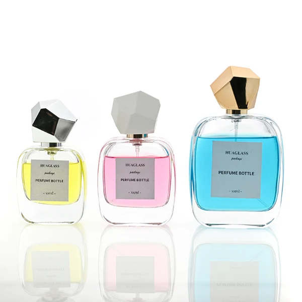 HUA0102 perfume bottle, rounded rectangular glass body with liquid, faceted geometric plastic cap, neck with bright gold metallic finish, modern elegant design, available in 30 ml, 50 ml, and 100 ml.
