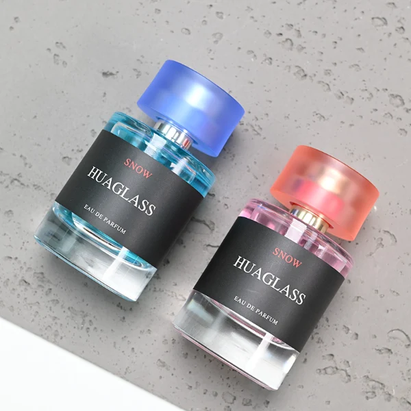 HUA0103 perfume bottle, cylindrical glass body with liquid, glossy colored plastic cap, neck with bright gold metallic finish, modern minimalist design, available in 30 ml, 50 ml, and 100 ml.