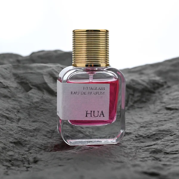 HUA0104 perfume bottle, rounded rectangular glass body with liquid and outer HUA label, cylindrical plastic cap with layered ring texture, modern elegant design, available in 30 ml, 50 ml, and 100 ml.